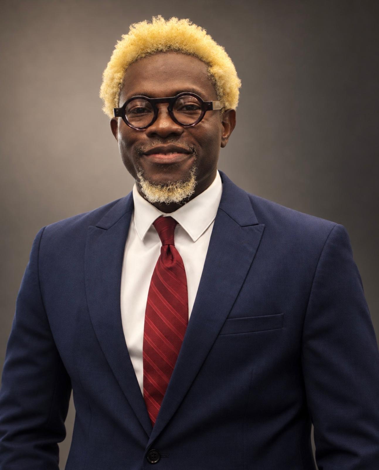 Dr. Ibrahim Dakubu wearing a navy suit and red tie